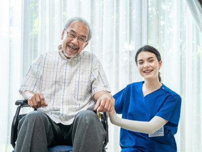 aide and senior man on wheelchair smiling and having photo together